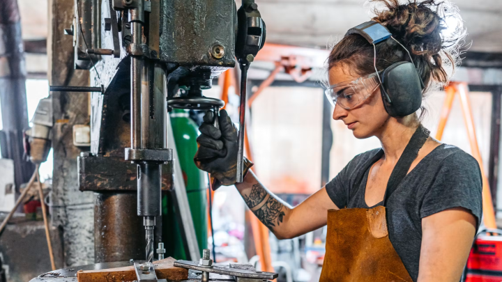 Woman using heavy machinery with protective headphones on